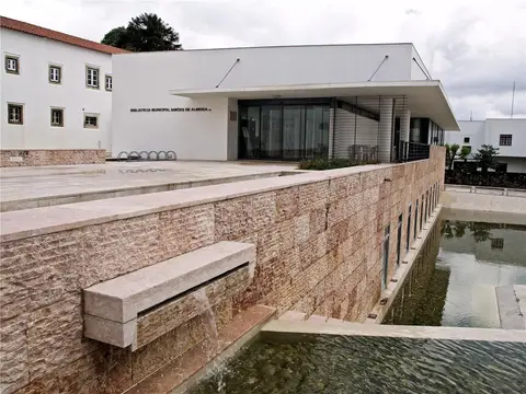 Exterior da Biblioteca Municipal Simões de Almeida, com espelho de água e muro de pedra
