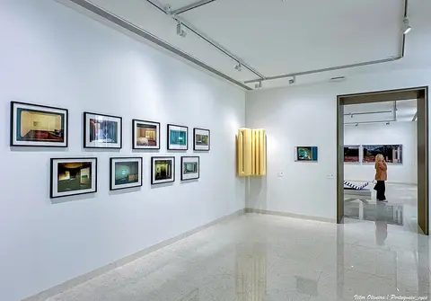 Sala de exposição do MACAM com fotografias emolduradas em paredes brancas e visitante ao fundo