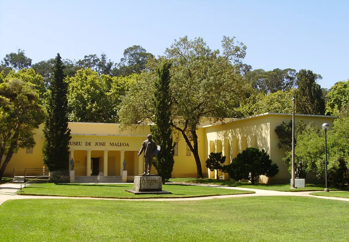 Edifício amarelo do Museu de José Malhoa, com estátua e relvado no Parque D. Carlos I