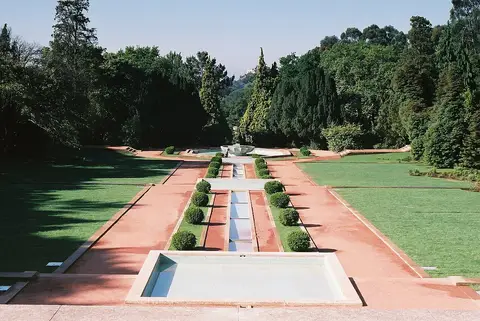 Jardim formal de Serralves com espelhos de água, buxos aparados e relvados ladeados por árvores.