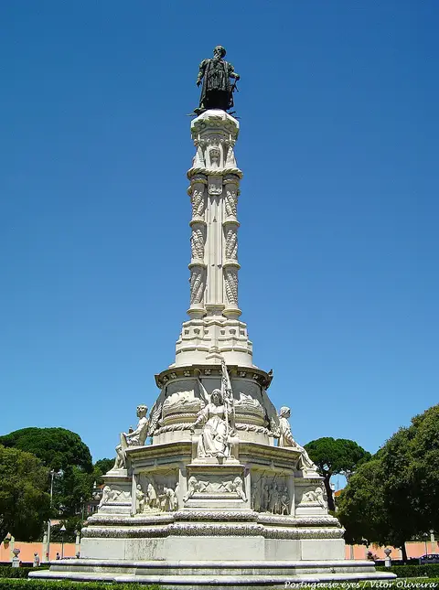 Monumento a Afonso de Albuquerque, coluna de pedra com estátua de bronze, sob céu azul