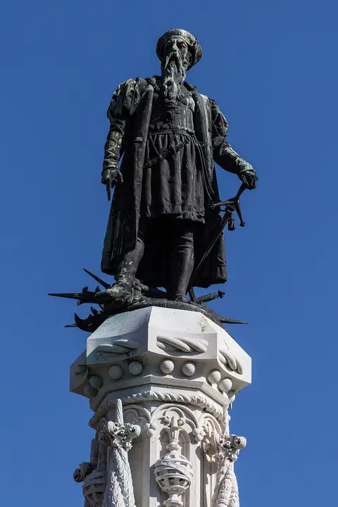 Estátua de bronze de Afonso de Albuquerque no topo do monumento, contra o céu azul