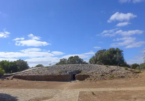 Monumento megalítico de Alcalar: montículo de pedras com entrada em corredor, sob céu azul