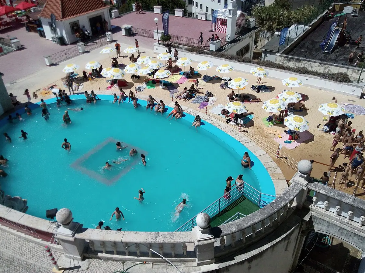 Vista de cima da praia urbana do Jardim do Torel, com piscina circular, areia e chapéus de sol