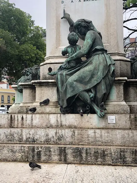 Base do monumento a Sá da Bandeira com grupo escultórico em bronze e pombos no pavimento