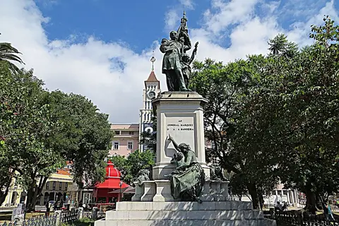 Monumento ao General Sá da Bandeira em jardim arborizado, com torre do relógio ao fundo