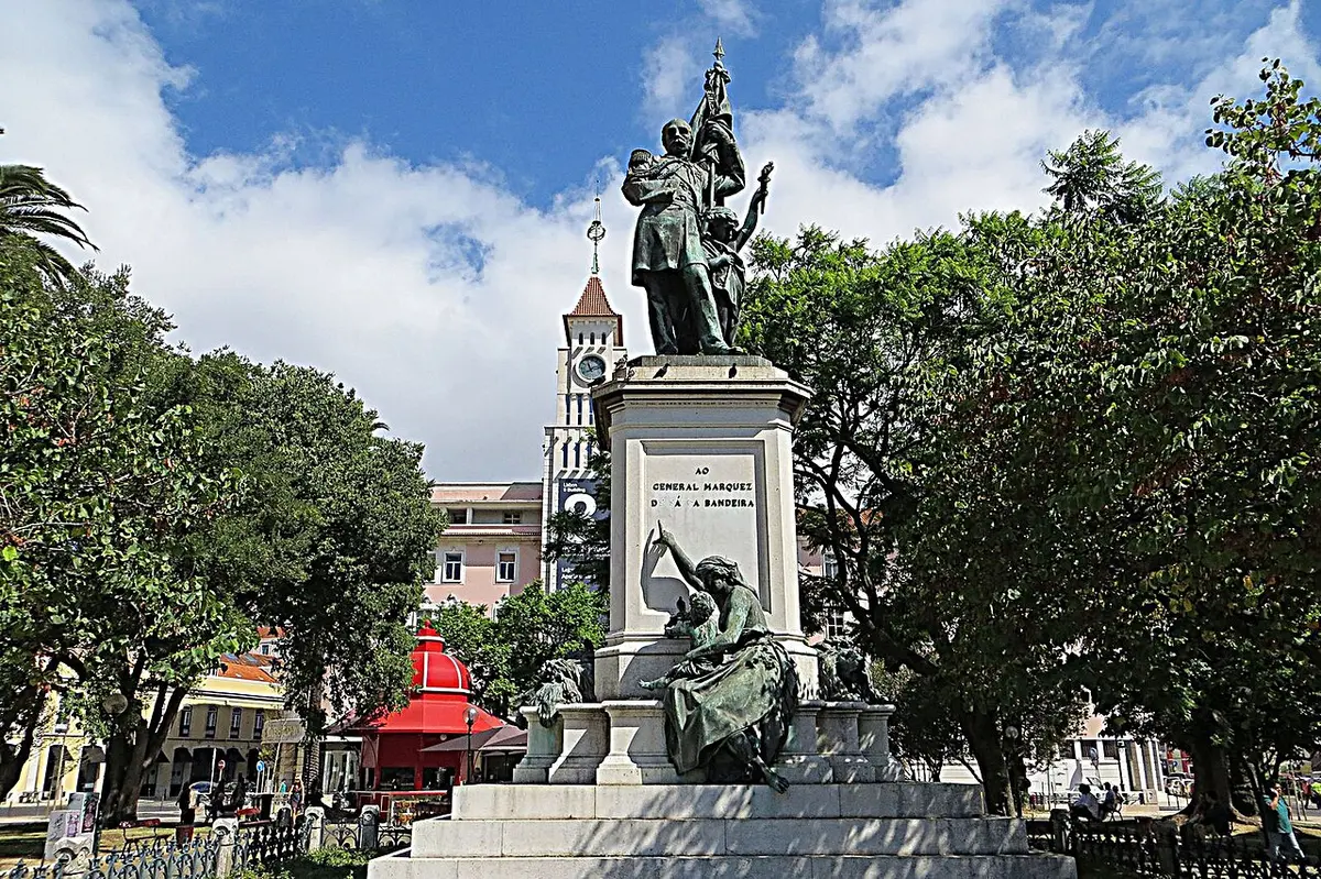 Monumento ao General Sá da Bandeira em jardim arborizado, com torre do relógio ao fundo