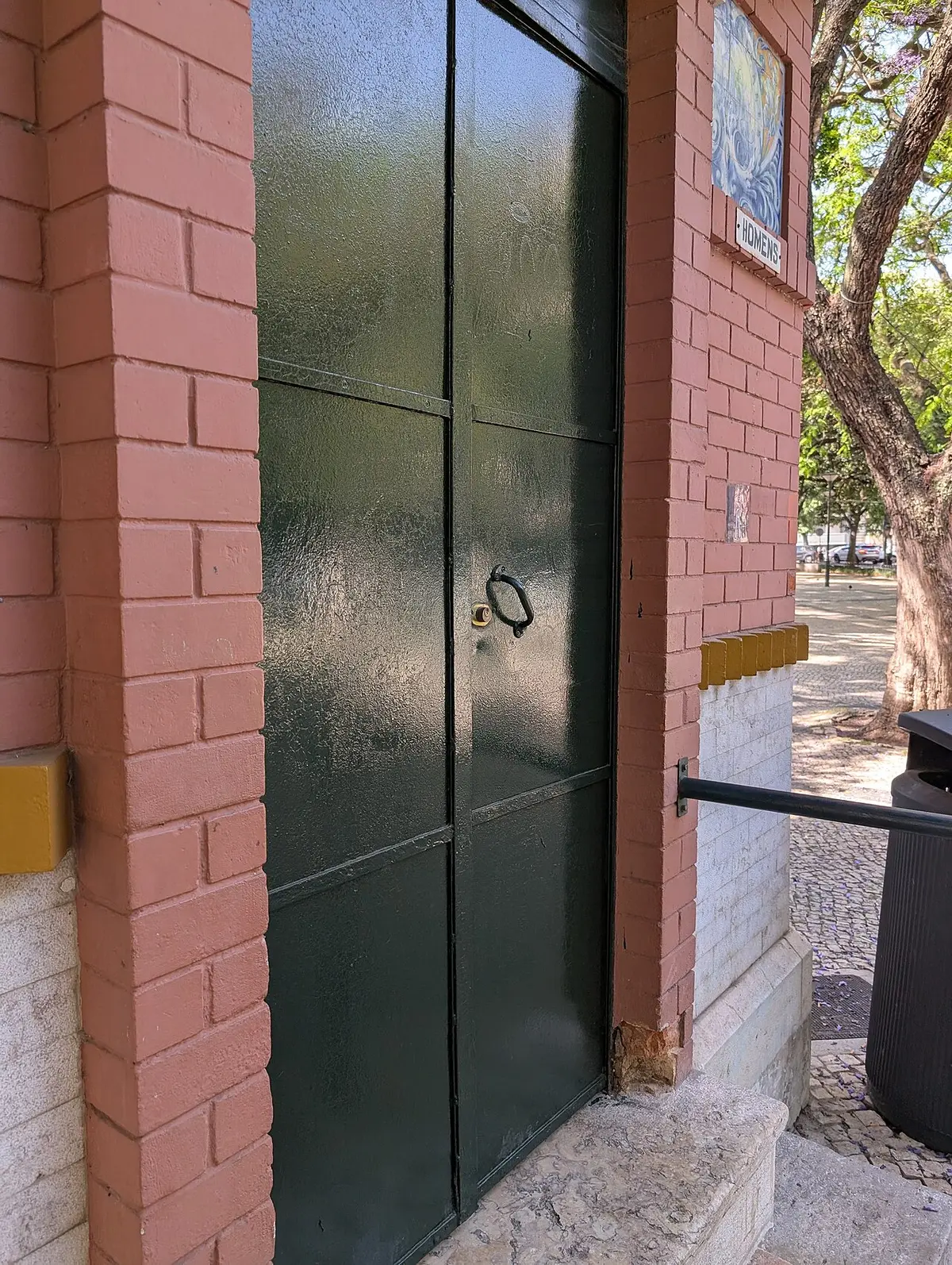 Porta verde fechada da casa de banho pública de tijolo no Jardim Constantino, em Lisboa