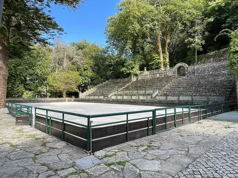 Anfiteatro ao ar livre com palco e bancadas de pedra rodeado de árvores no Parque da Liberdade, Sintra