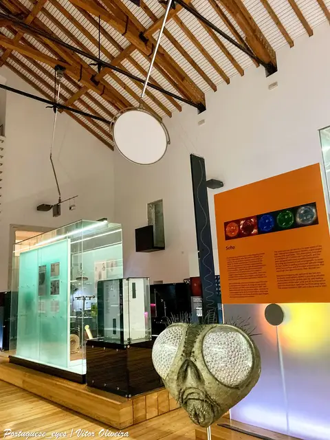 Interior do Museu da Ciência de Coimbra com vitrina, painel expositivo e modelo gigante de cabeça de mosca