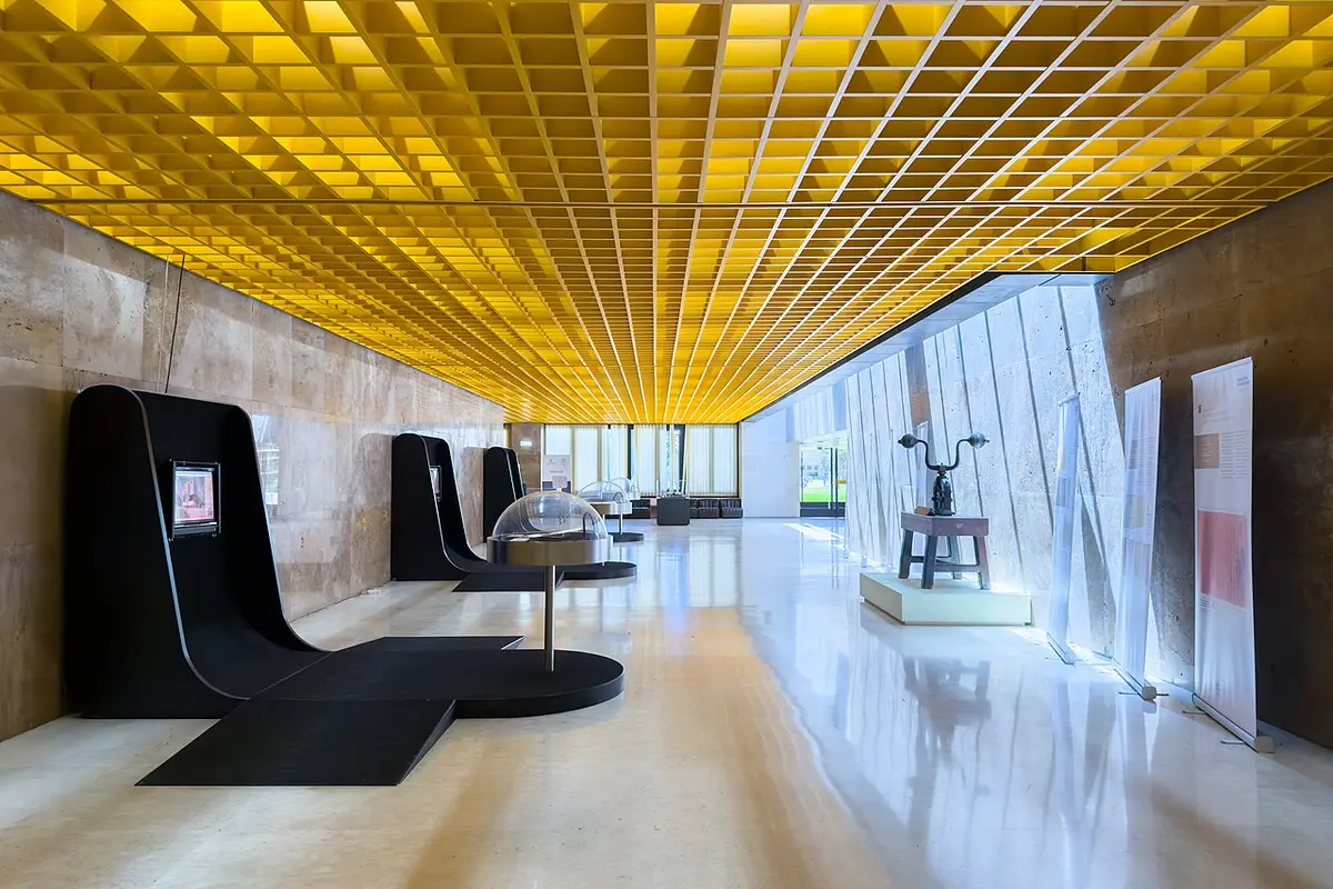 Interior do Arquivo Nacional da Torre do Tombo com teto amarelo em grelha e zona de exposição
