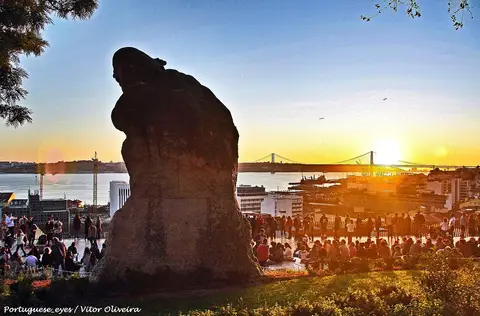Miradouro de Santa Catarina ao pôr do sol, com a estátua do Adamastor e a Ponte 25 de Abril ao fundo