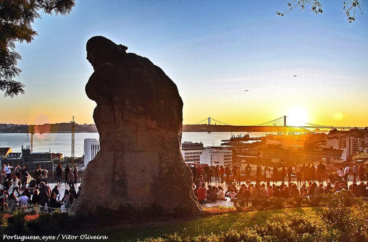 Miradouro de Santa Catarina ao pôr do sol, com a estátua do Adamastor e a Ponte 25 de Abril ao fundo