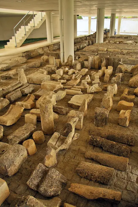 Blocos de pedra e elementos arquitetónicos em exposição num espaço coberto do Mosteiro de Santa Clara-a-Velha