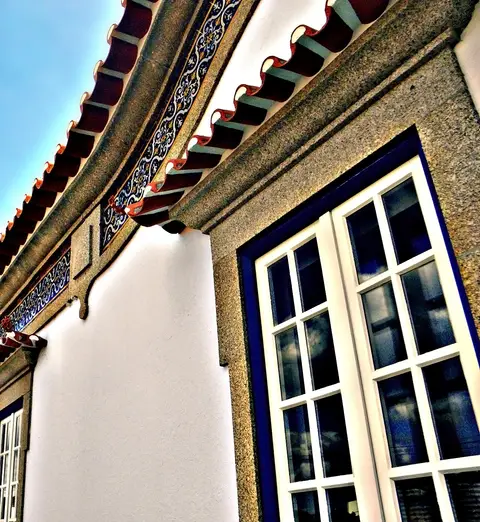 Pormenor da fachada do Museu das Terras de Basto, com beirado de telha, friso de azulejos e janelas brancas