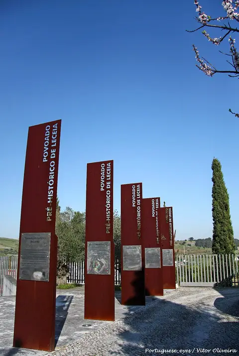 Painéis verticais em aço corten com a inscrição "Povoado Pré-Histórico de Leceia", à entrada do sítio.