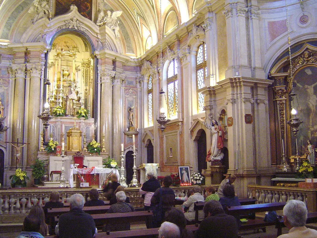 Interior barroco da Igreja de Santo António, em Lisboa, com altar dourado e fiéis nos bancos