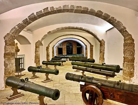 Sala abobadada com arcos de pedra e coleção de canhões antigos no Museu Militar de Lisboa