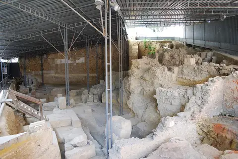Ruínas do Teatro Romano de Lisboa protegidas por cobertura metálica, com estruturas de pedra escavadas
