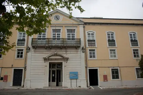 Fachada principal do edifício do Hospital Miguel Bombarda, com relógio e varanda de ferro forjado.