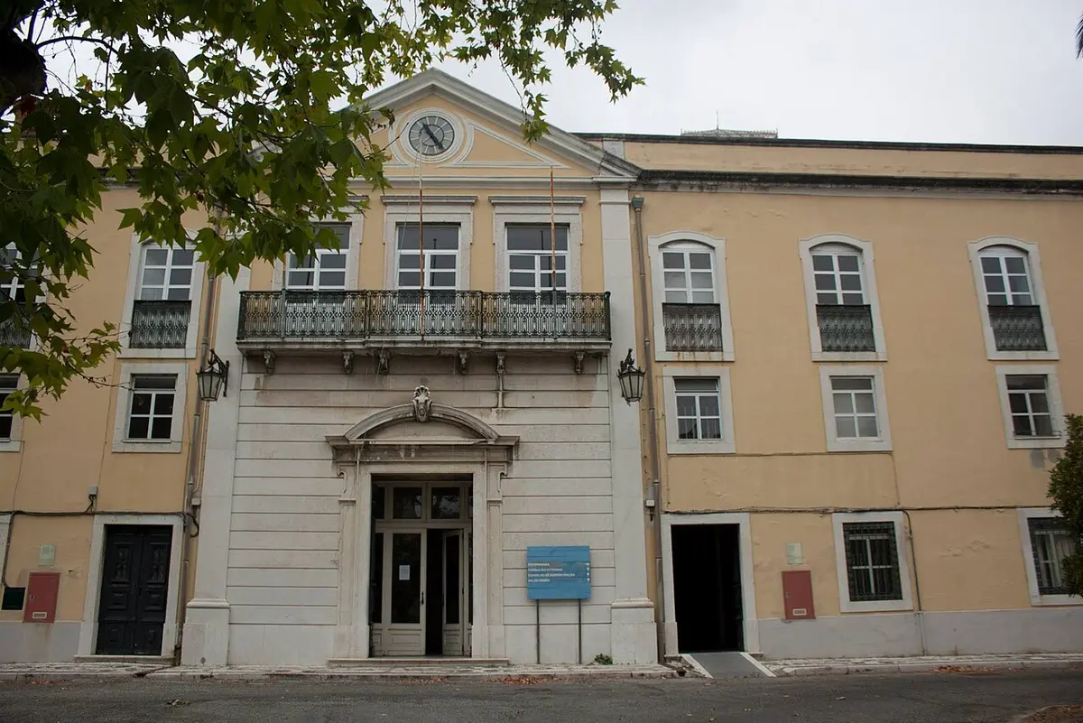 Fachada principal do edifício do Hospital Miguel Bombarda, com relógio e varanda de ferro forjado.