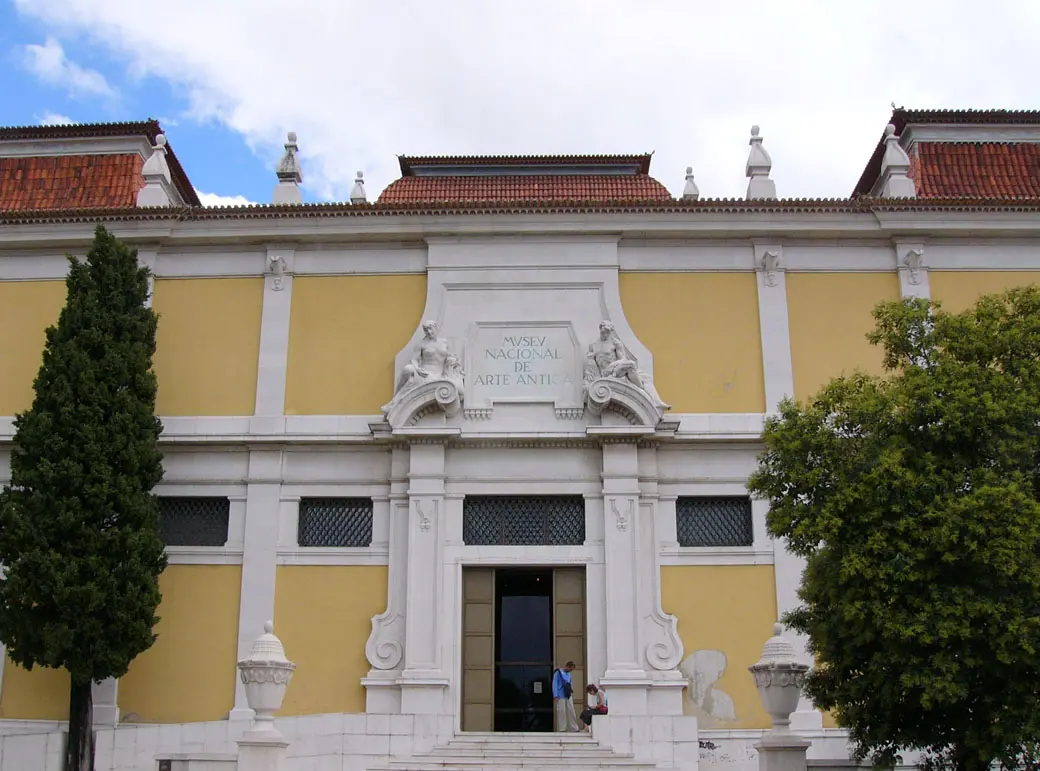 Fachada amarela e branca do Museu Nacional de Arte Antiga, em Lisboa, com entrada principal