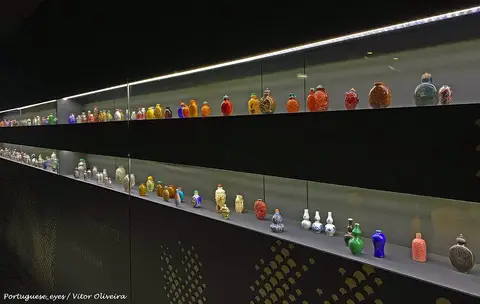 Vitrina iluminada do Museu do Oriente com coleção de pequenos frascos de rapé coloridos