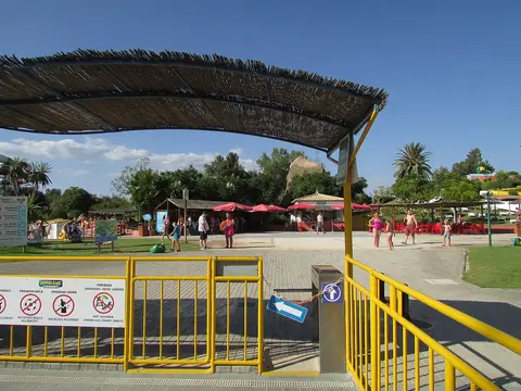 Entrada do parque aquático Aqualand Algarve com cobertura de colmo, gradeamento amarelo e placas de regras