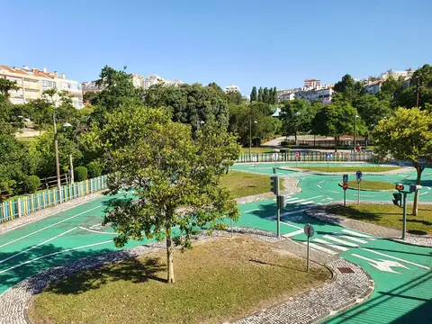 Circuito de educação rodoviária com piso verde, sinais e semáforos num parque urbano arborizado