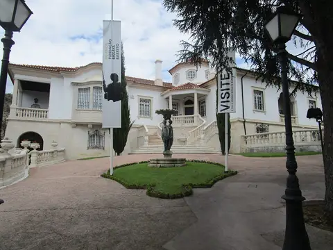 Entrada principal da Casa Museu Bissaya Barreto, com jardim, fonte e bandeirolas da fundação
