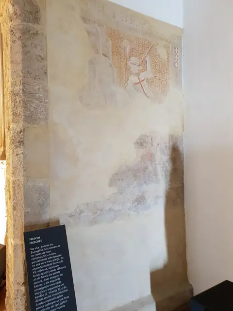 Parede interior com vestígios de frescos medievais e painel informativo na Igreja de Santa Maria do Castelo