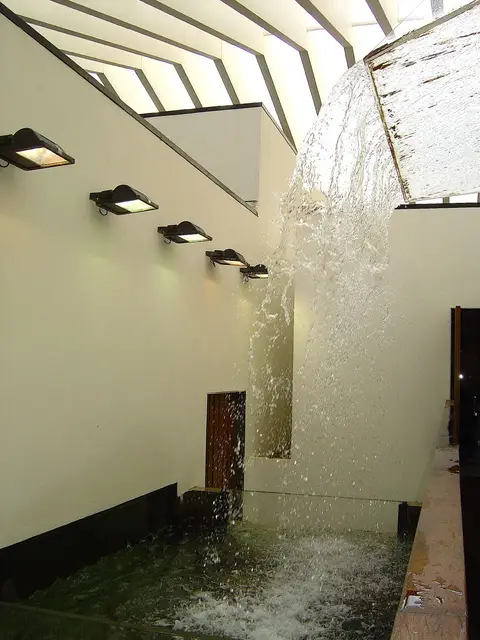 Queda de água no interior do Fluviário de Mora, com tanque e candeeiros na parede