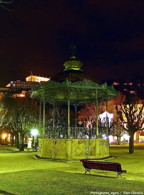 Coreto de ferro iluminado à noite no Parque Doutor Manuel Braga, em Coimbra, com banco e relva