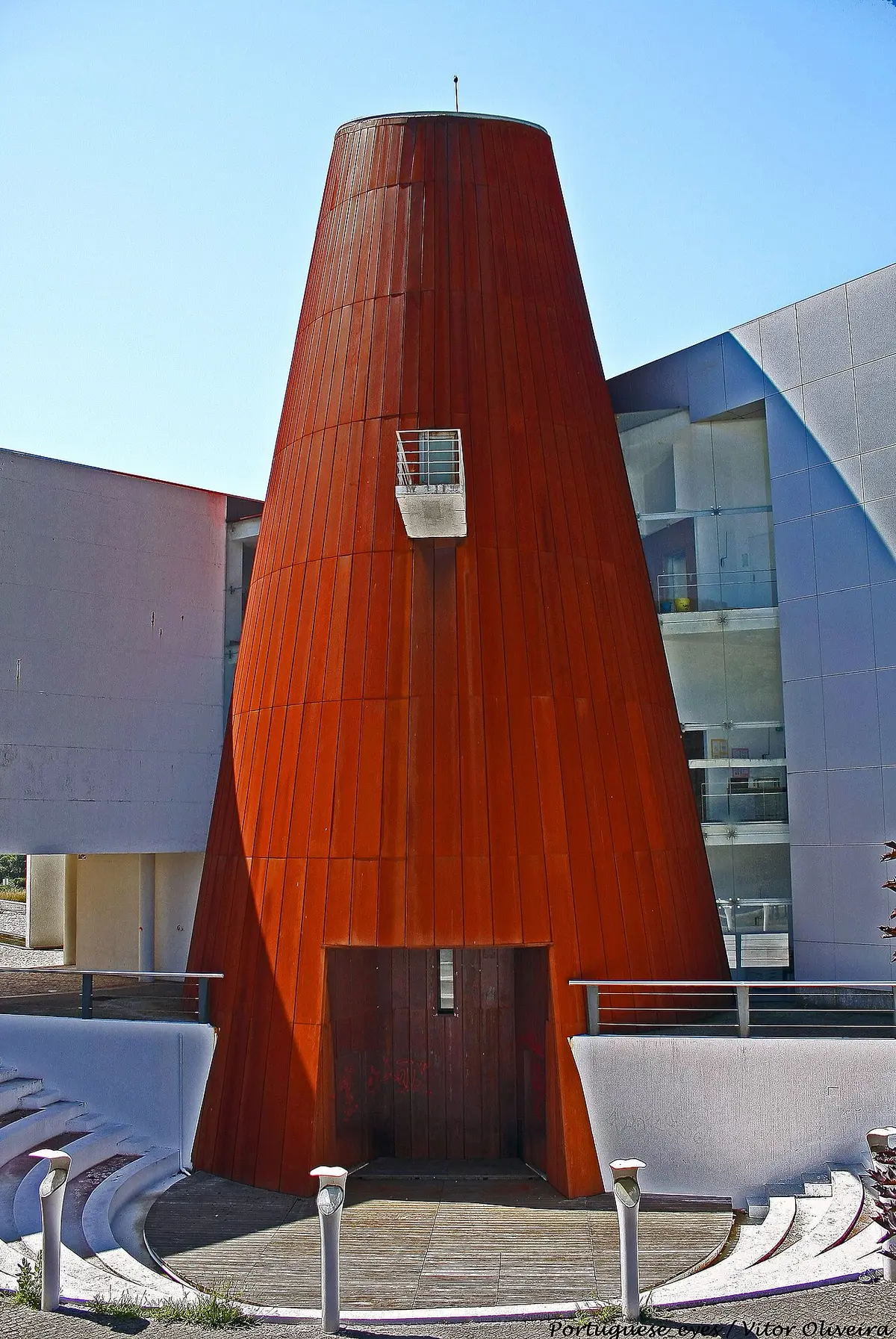 Torre cónica revestida a metal cor de ferrugem na Biblioteca Municipal de Valongo, com anfiteatro exterior