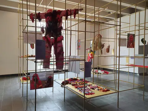 Sala de exposição com estruturas metálicas douradas, trajes de máscaras e máscaras tradicionais expostas
