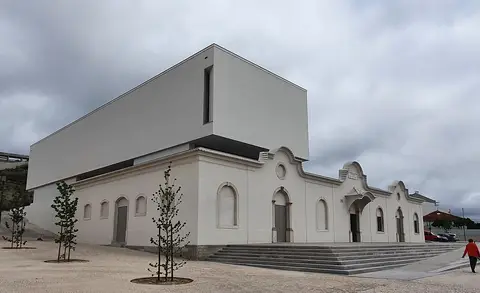 Exterior do Centro de Artes e Criatividade, edifício branco com volume moderno sobre fachada antiga
