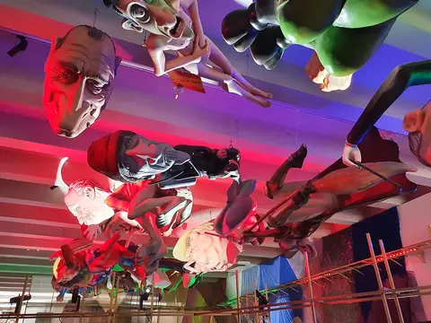 Figuras de carnaval suspensas no teto, com iluminação colorida, no Centro de Artes e Criatividade
