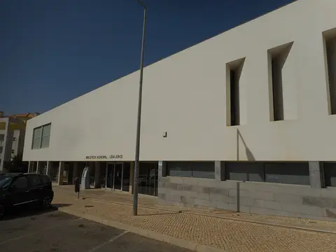 Fachada branca da Biblioteca Municipal Lídia Jorge, em Albufeira, com letreiro sobre a entrada