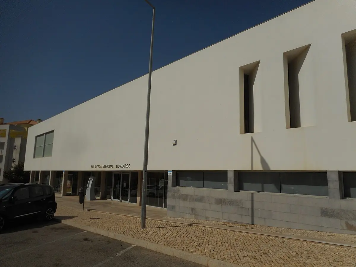 Fachada branca da Biblioteca Municipal Lídia Jorge, em Albufeira, com letreiro sobre a entrada