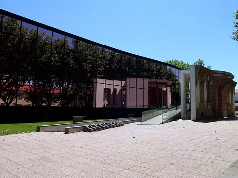 Edifício moderno da Biblioteca Municipal Rocha Peixoto, com fachada de vidro escuro e pátio em pedra