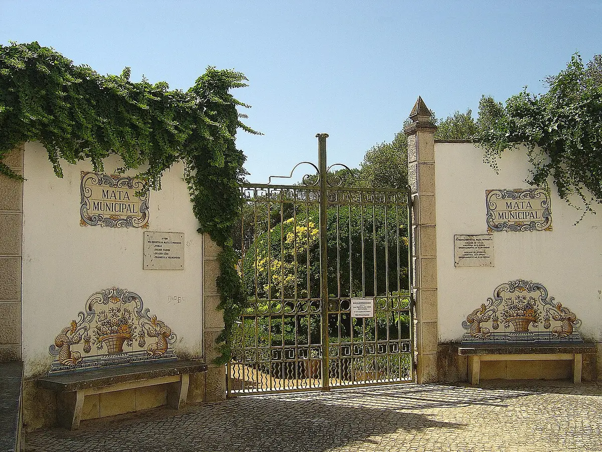 Portão de ferro da Mata Municipal do Bombarral, com painéis de azulejos e bancos junto ao muro