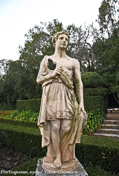 Estátua de pedra em jardim com sebes recortadas e árvores na Mata Municipal do Bombarral