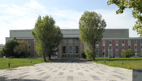 Fachada principal da Biblioteca Nacional de Portugal, em Lisboa, com árvores e calçada em xadrez