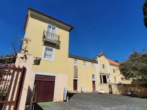 Edifício amarelo da Casa e Quinta do Conventinho, em Loures, com igreja anexa e pátio empedrado.