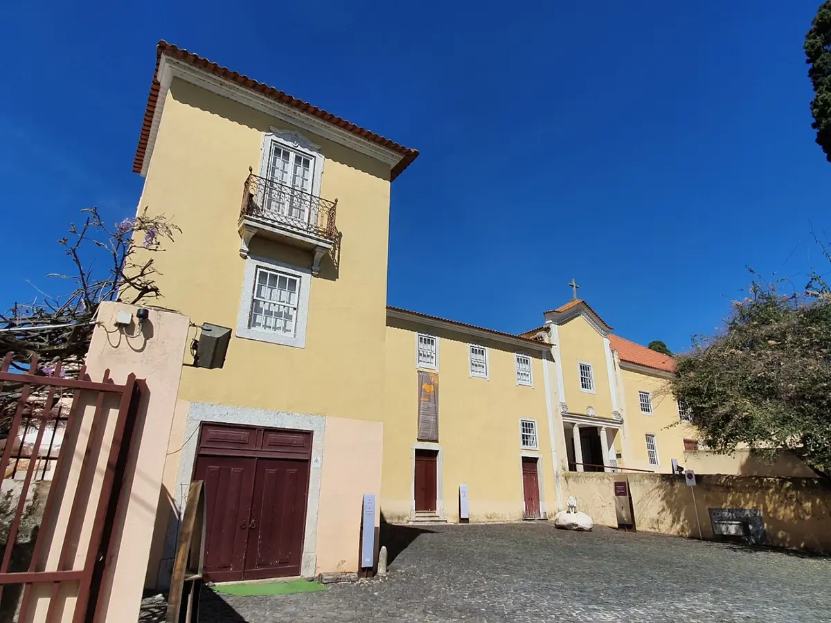 Edifício amarelo da Casa e Quinta do Conventinho, em Loures, com igreja anexa e pátio empedrado.