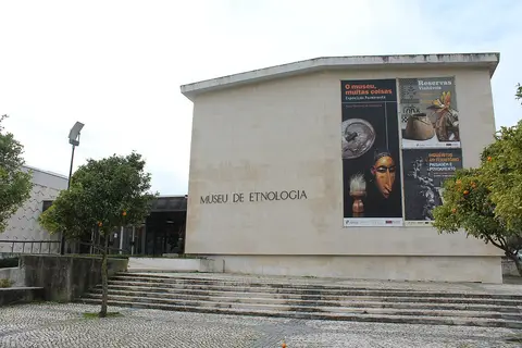 Fachada do Museu Nacional de Etnologia em Lisboa, com cartazes de exposições e escadaria de acesso