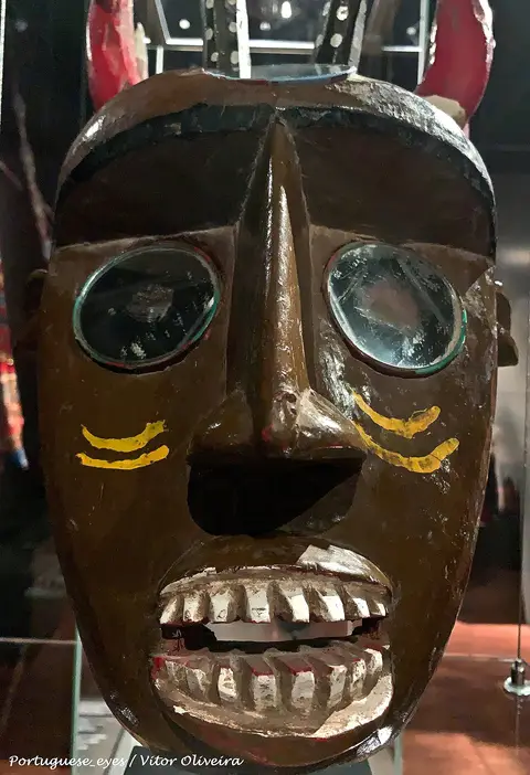 Máscara tradicional de madeira pintada exposta em vitrina no Museu Nacional de Etnologia