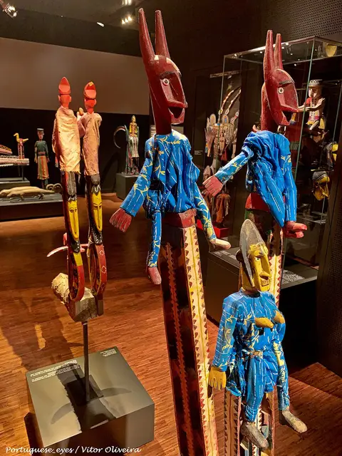 Marionetas africanas de madeira com túnicas azuis expostas numa sala do Museu Nacional de Etnologia