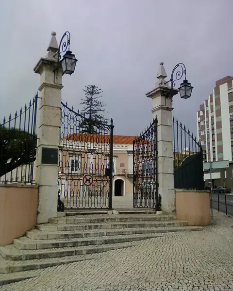 Portão de ferro com candeeiros e escadaria à entrada do Palácio Ribamar, em Algés