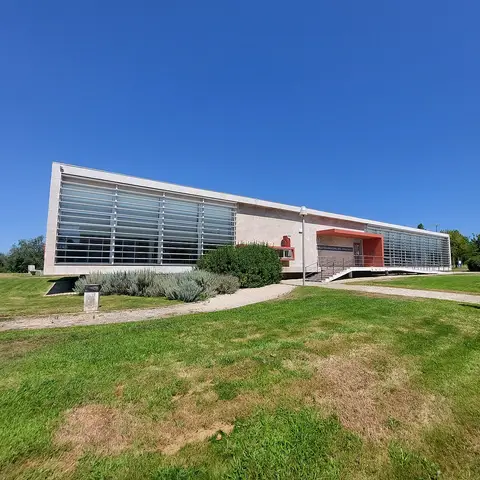 Fachada moderna da Biblioteca Municipal de Condeixa-a-Nova, com relvado e céu azul